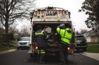 Haulers empty garbage into the compactor of their truck in Bowie, Maryland on April 9, 2018. Safety regulations require workers to wear reflective clothing to mitigate risk from traffic hazards, but dangers like pool chemicals, needles and even weapons are ever-present in the garbage. (Aaron Rosa/Capital News Service)