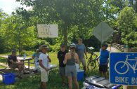 Jon Sperling speaks to bike riders about development at the Patuxent Branch Trail, while. Loc Nguyen holds a sign. Jerry Ueckerman and Min Sperling are seated, while organizer Wayne Davis looks for the next passerby. (Photo by Ricardo Whitaker)