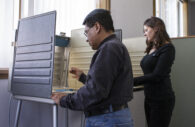 Stock photo of two people at voting booths.